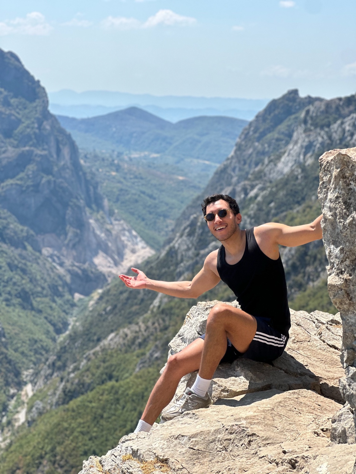 Keny sentado en una roca, rodeado de montañas